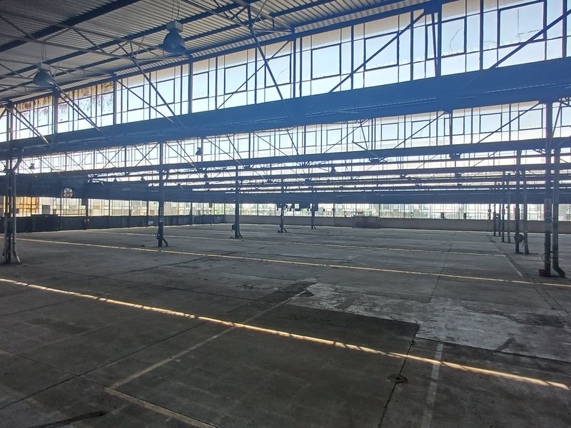 Expansive industrial warehouse space featuring high ceilings, steel structural framing, and extensive clerestory windows providing abundant natural light.