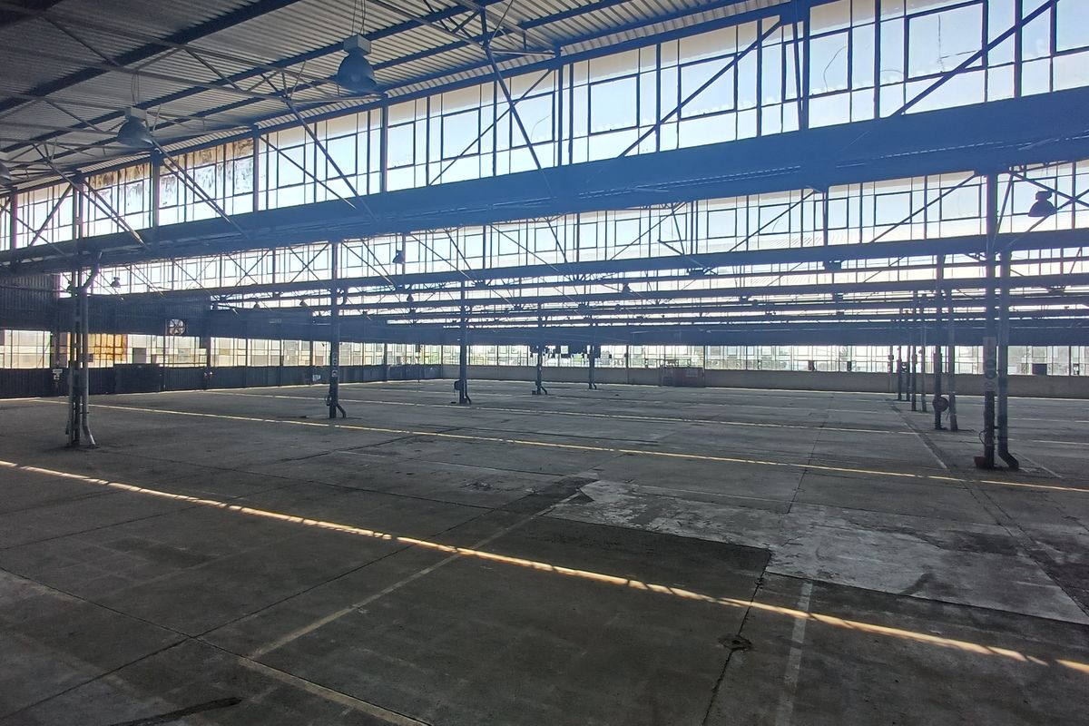 Expansive industrial warehouse space featuring high ceilings, steel structural framing, and extensive clerestory windows providing abundant natural light.