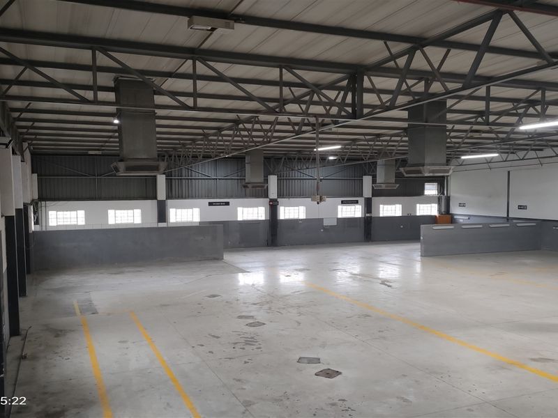 Spacious industrial warehouse unit featuring high exposed steel truss ceilings, concrete flooring, and integrated ventilation systems, suitable for storage or manufacturing operations.