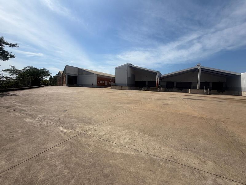 Expansive industrial concrete yard providing ample space for vehicle maneuvering and logistics operations, featuring multiple loading bays and warehouse access points.