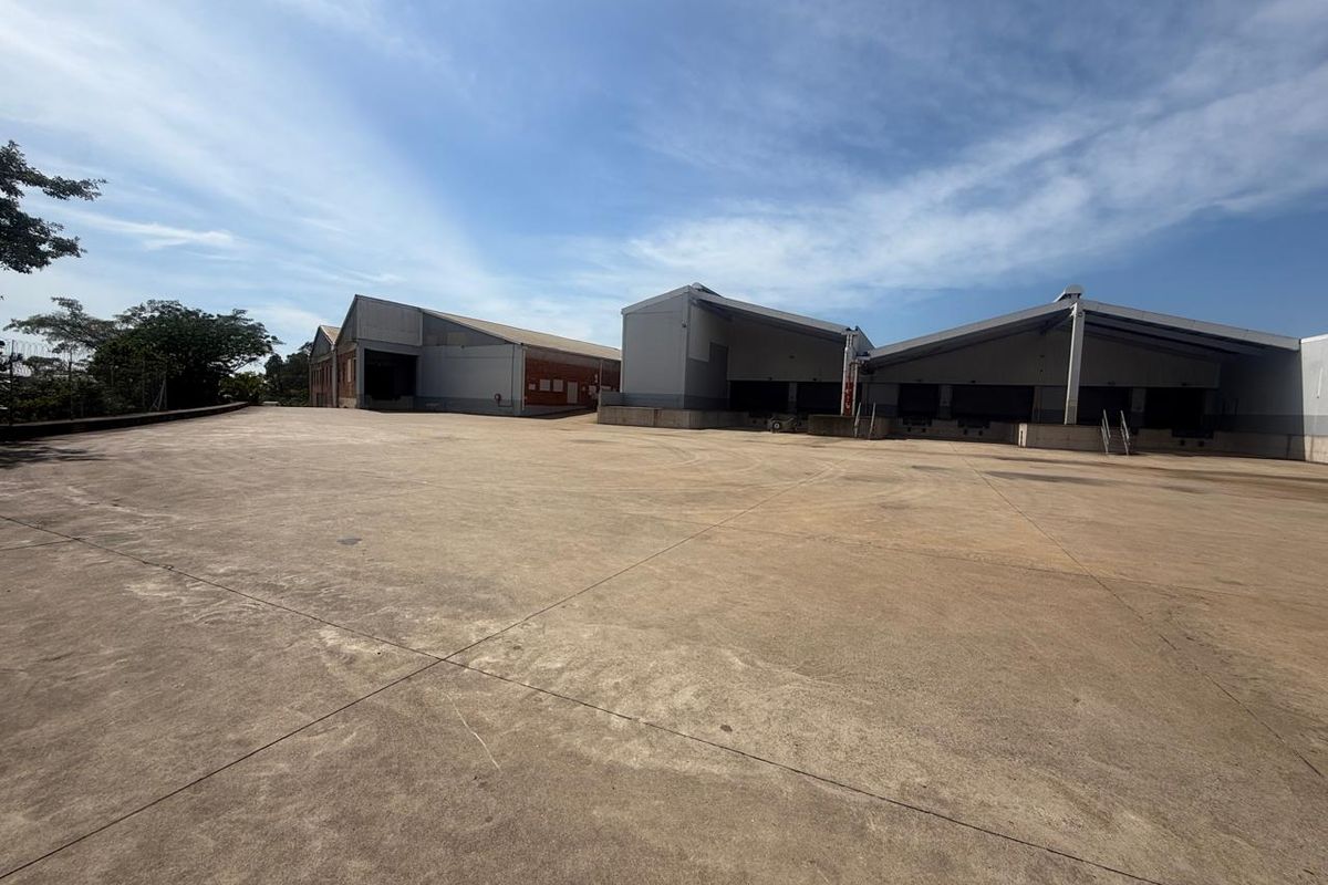 Expansive industrial concrete yard providing ample space for vehicle maneuvering and logistics operations, featuring multiple loading bays and warehouse access points.