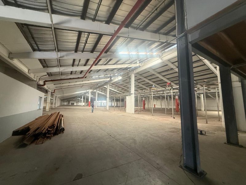 Expansive industrial warehouse space featuring high ceilings, exposed steel structural beams, concrete flooring, and open-plan layout suitable for manufacturing or storage operations.