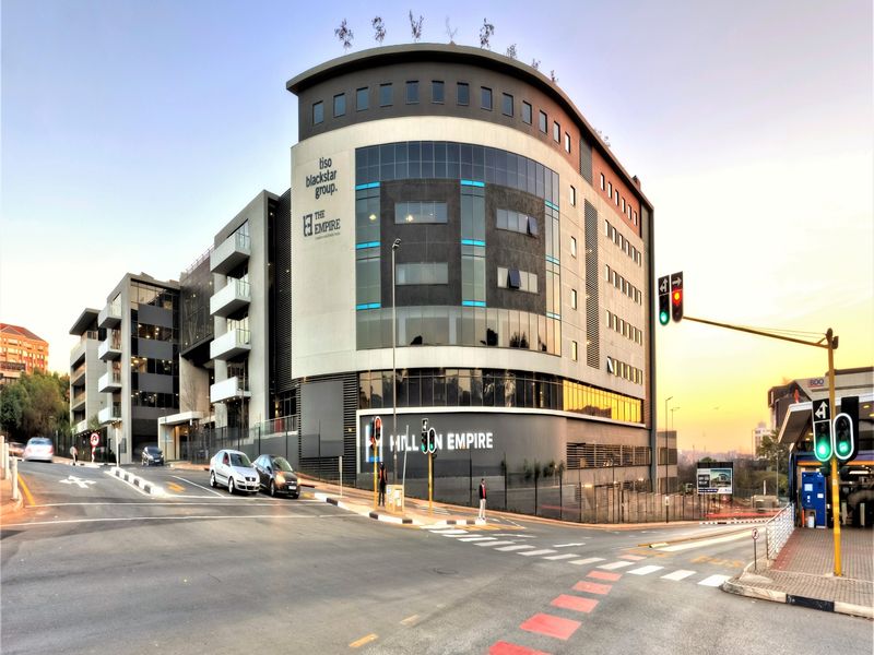 Modern multi-story commercial office building featuring contemporary glass and metal facade, prominent street-level signage, and integrated parking facilities.