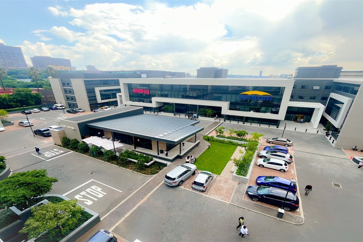 Aerial view of a modern commercial office complex featuring landscaped gardens, paved parking facilities, and contemporary building architecture.