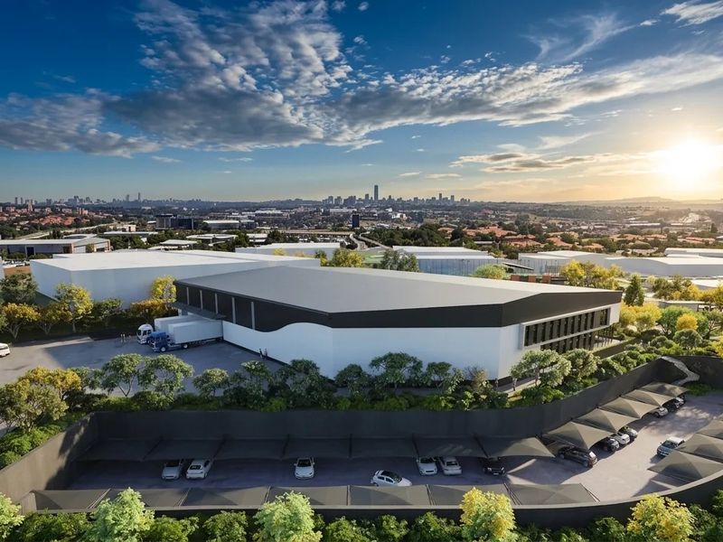 Aerial view of a modern industrial warehouse facility featuring a dedicated loading bay, extensive asphalt parking, and covered shade cloth parking bays.