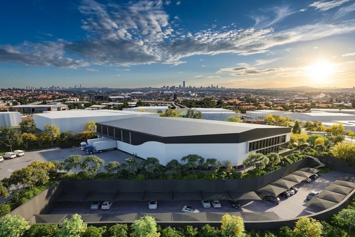 Aerial view of a modern industrial warehouse facility featuring a dedicated loading bay, extensive asphalt parking, and covered shade cloth parking bays.