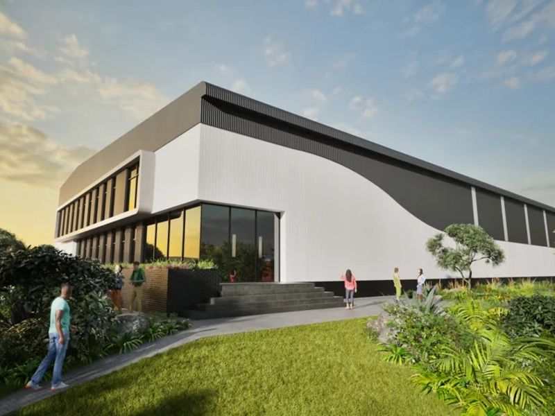 A modern industrial building featuring sleek metal cladding, large glass windows, and a landscaped entrance area.