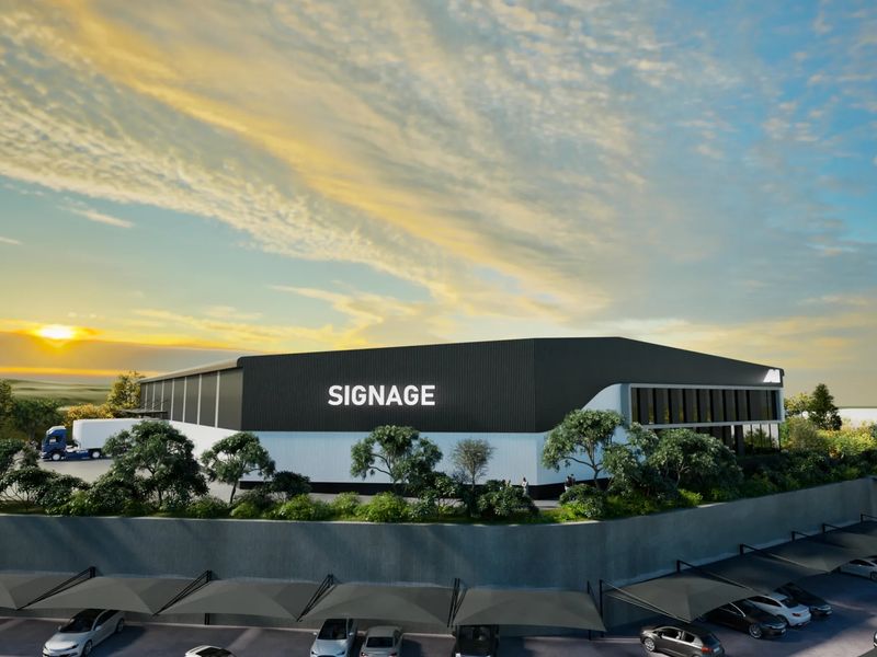 Modern industrial warehouse facility featuring corrugated metal cladding, a dedicated loading bay, and extensive covered parking infrastructure.