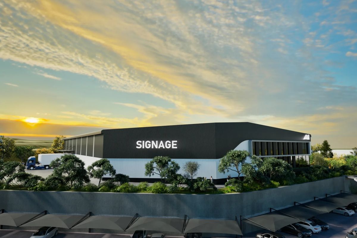 Modern industrial warehouse facility featuring corrugated metal cladding, a dedicated loading bay, and extensive covered parking infrastructure.
