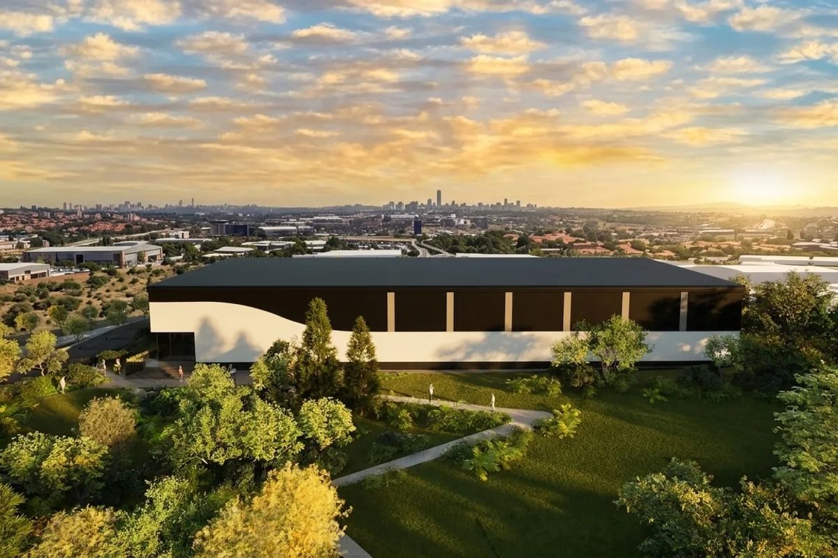 Aerial view of a modern industrial warehouse facility set within landscaped grounds, featuring a clean architectural design and expansive surrounding area.