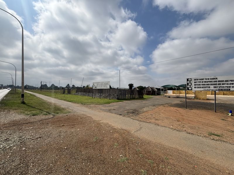Exterior view of the property entrance featuring gravel access, perimeter fencing, and signage for the retail site.