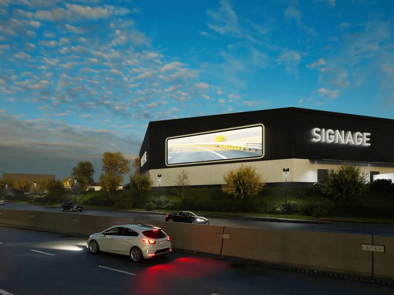 A modern industrial property featuring a prominent digital billboard and high-visibility signage, situated along a major roadway.
