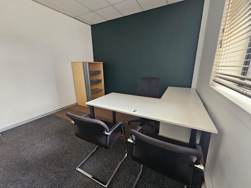A functional office space featuring a suspended ceiling, carpeted flooring, and venetian blinds, providing a professional environment for business operations.