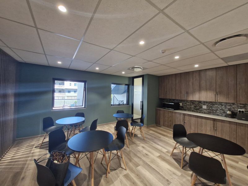 Modern commercial office space featuring built-in cabinetry, stone-look backsplash, suspended ceiling with recessed lighting, and durable laminate flooring.
