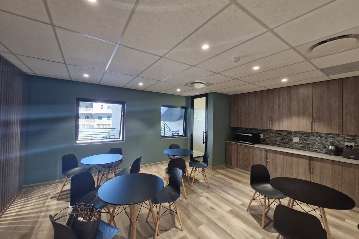 Modern commercial office space featuring built-in cabinetry, stone-look backsplash, suspended ceiling with recessed lighting, and durable laminate flooring.