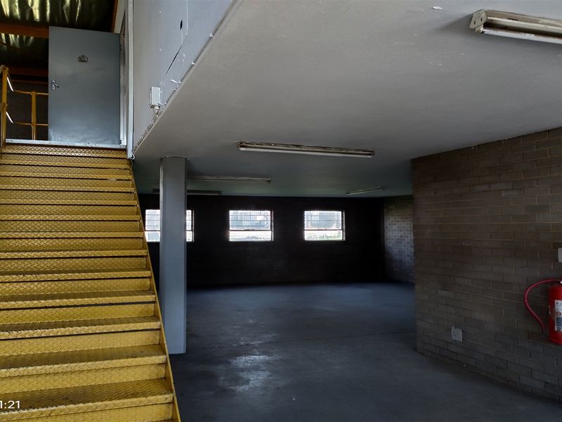 Industrial utility space featuring exposed brick walls, concrete flooring, and a prominent yellow metal staircase leading to an upper level.