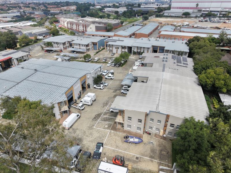 Aerial view of an industrial park complex featuring multiple warehouse buildings, paved parking areas, and solar panel installations on the roofs.