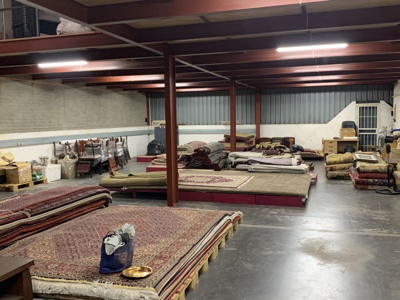 Spacious industrial utility area featuring exposed steel structural beams, a mezzanine level, concrete flooring, and functional overhead lighting.