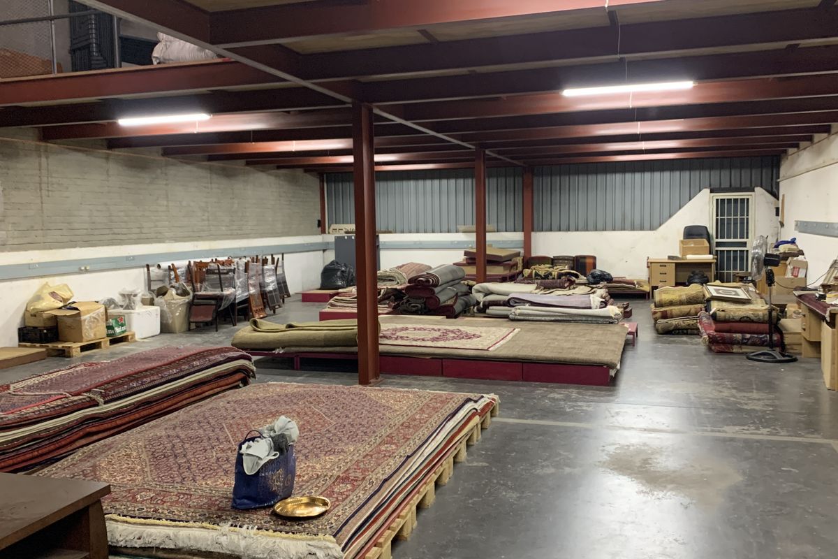 Spacious industrial utility area featuring exposed steel structural beams, a mezzanine level, concrete flooring, and functional overhead lighting.
