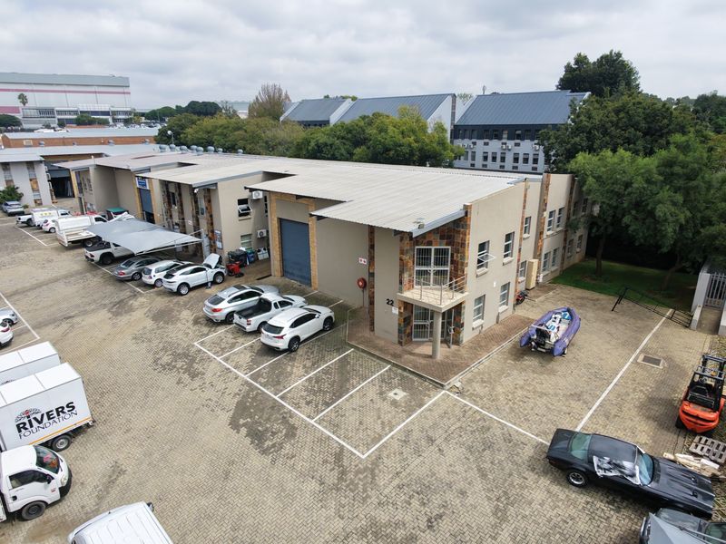 Aerial view of an industrial complex featuring multiple warehouse units, paved parking facilities, and stone-clad exterior detailing.
