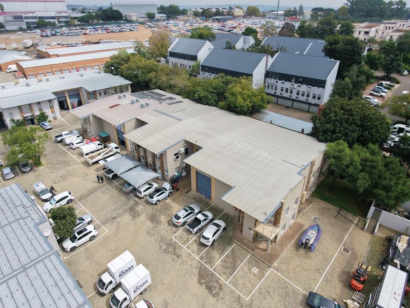 Aerial view of an industrial property complex featuring multiple warehouse units, metal roofing, and extensive paved parking facilities.