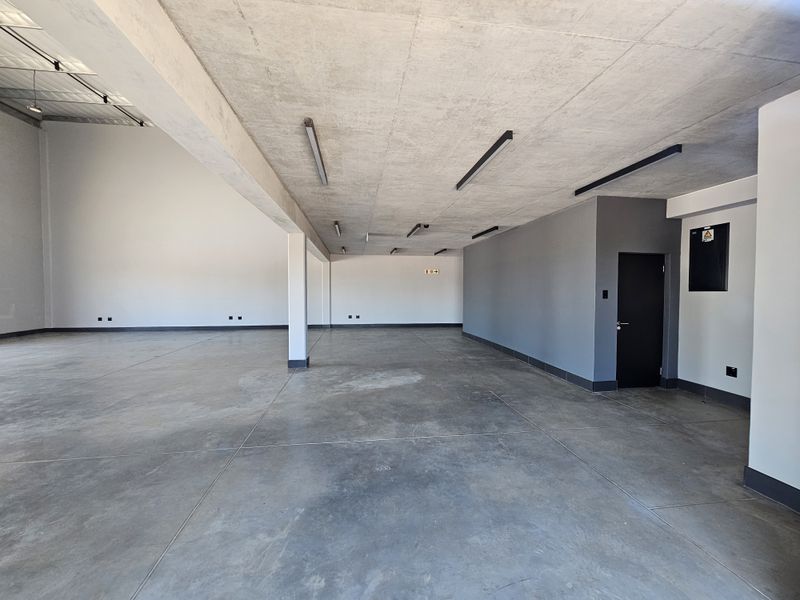 Spacious open-plan retail or industrial unit featuring polished concrete flooring, exposed concrete ceiling, and modern recessed lighting.