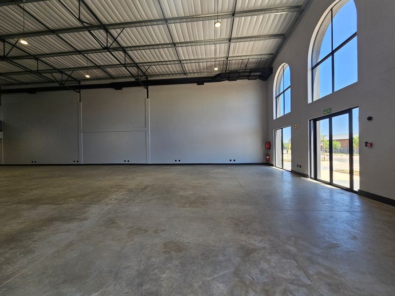 Spacious open-plan retail unit featuring high ceilings, polished concrete flooring, and large arched windows providing ample natural light.