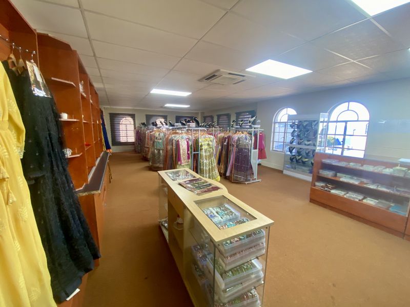 A commercial retail space featuring suspended ceilings, recessed lighting, ducted air conditioning, and arched windows with built-in display shelving.