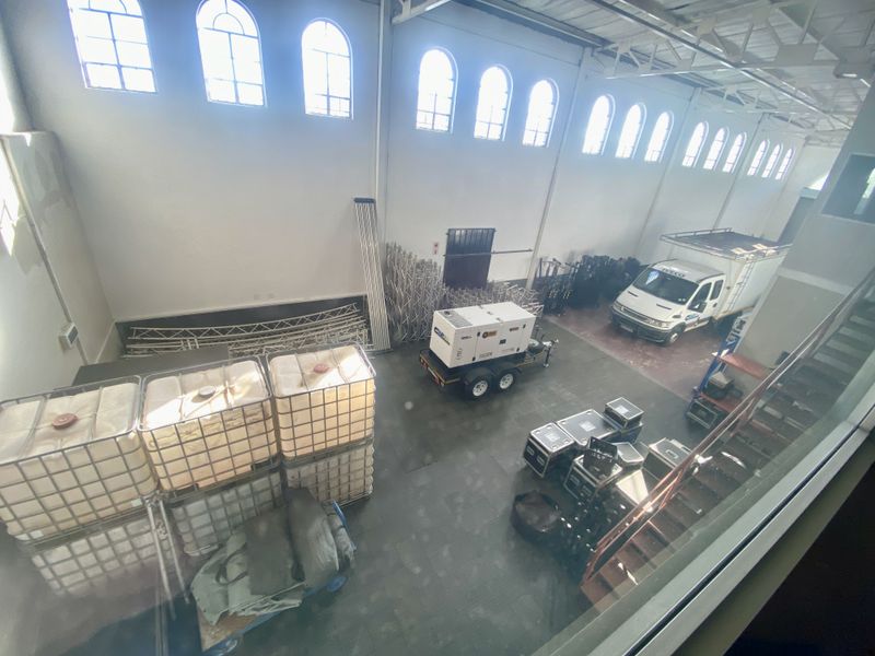 Spacious industrial warehouse featuring high ceilings, arched clerestory windows, exposed steel roof trusses, and durable concrete flooring, suitable for storage or light industrial operations.