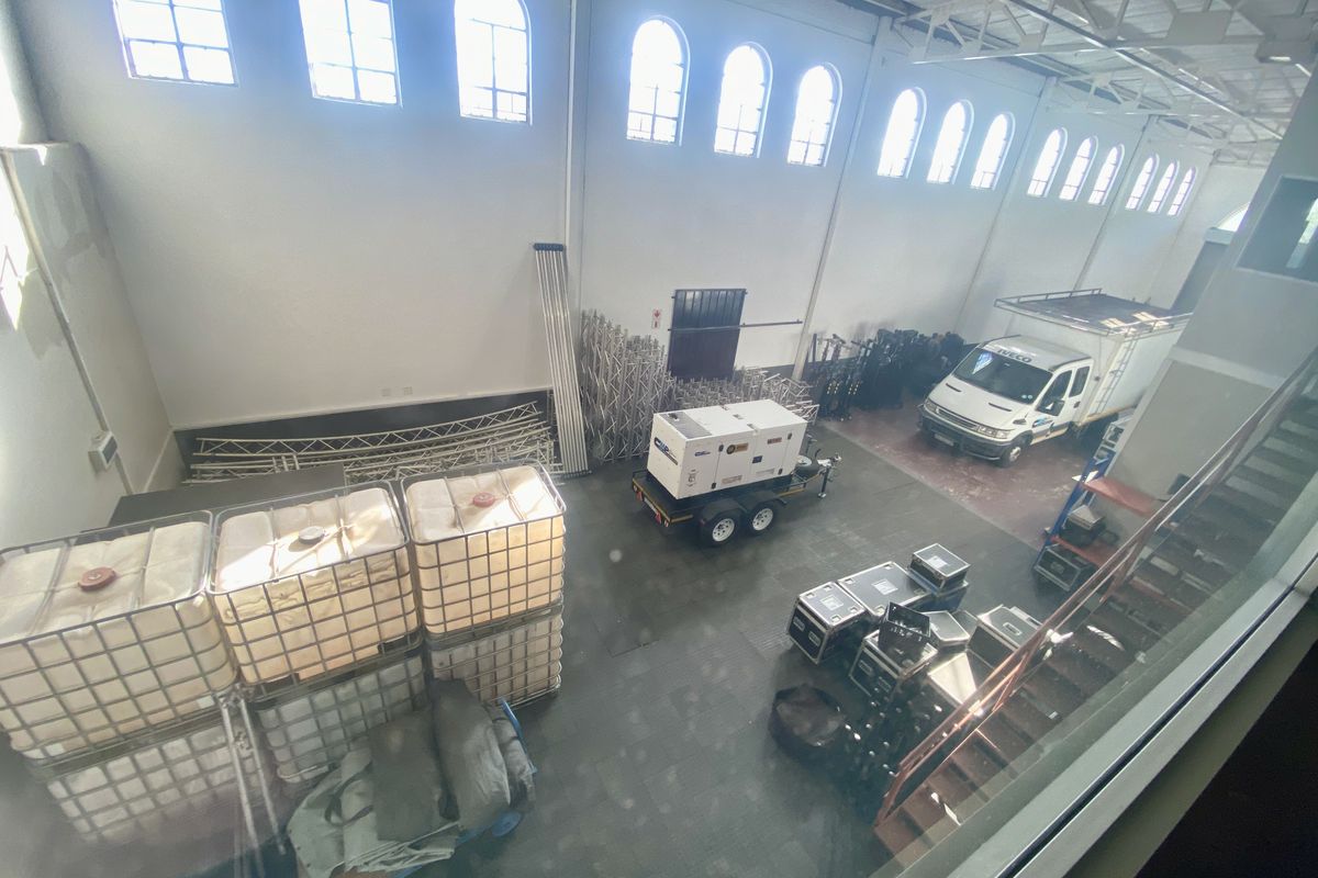 Spacious industrial warehouse featuring high ceilings, arched clerestory windows, exposed steel roof trusses, and durable concrete flooring, suitable for storage or light industrial operations.