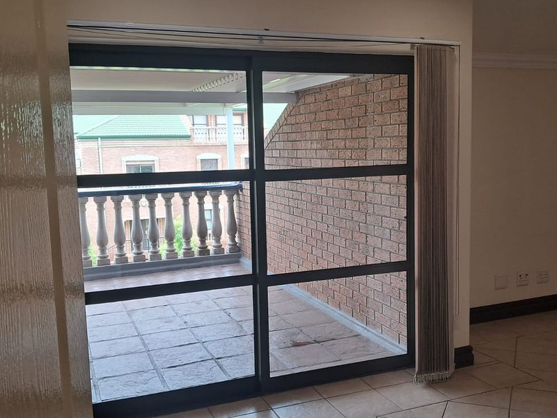 An interior office space featuring large sliding glass doors that open onto a private balcony with brick walls and a balustrade.