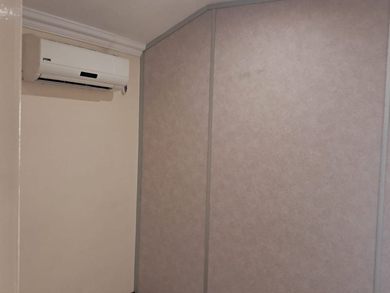 A functional office space featuring a wall-mounted air conditioning unit and modular partition walling.
