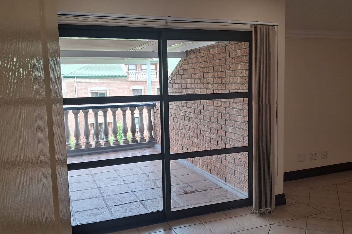 An interior office space featuring large sliding glass doors that open onto a private balcony with brick walls and a balustrade.