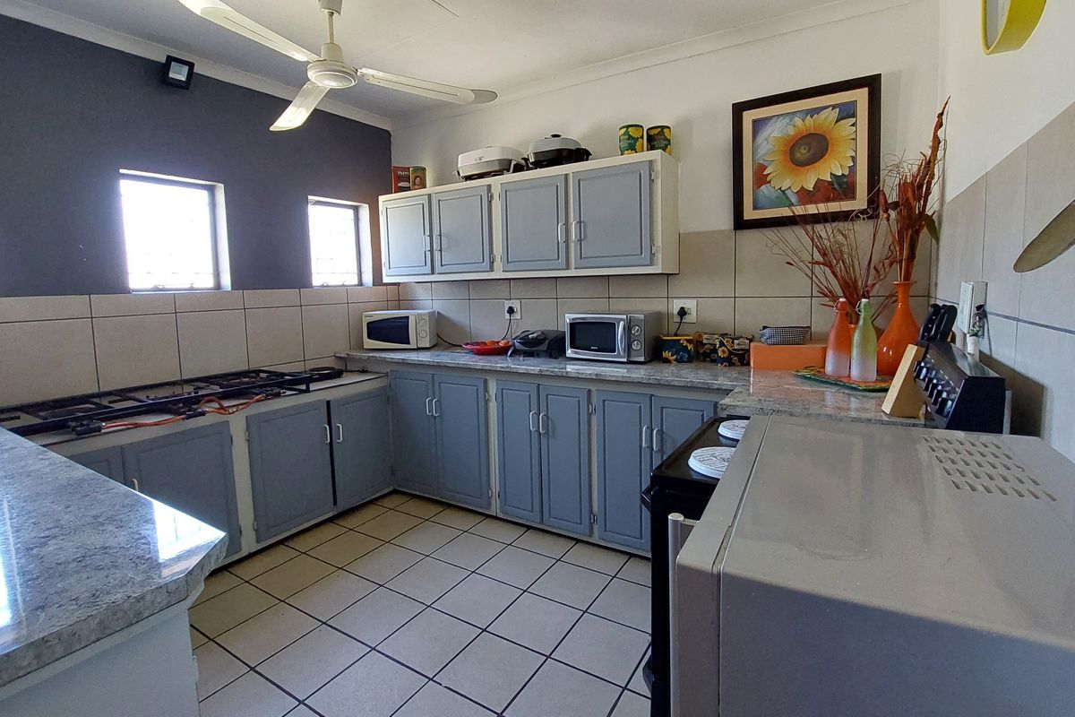 A functional kitchen featuring built-in cabinetry, a gas hob, tiled backsplash, and stone-look countertops, providing a practical workspace for meal preparation.