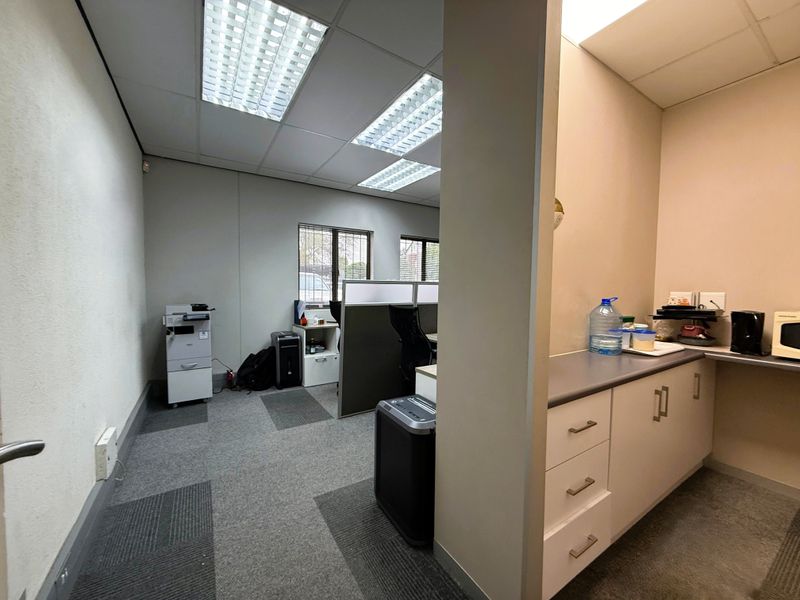 Functional office space featuring a kitchenette area with built-in cabinetry, carpeted flooring, and recessed ceiling lighting.