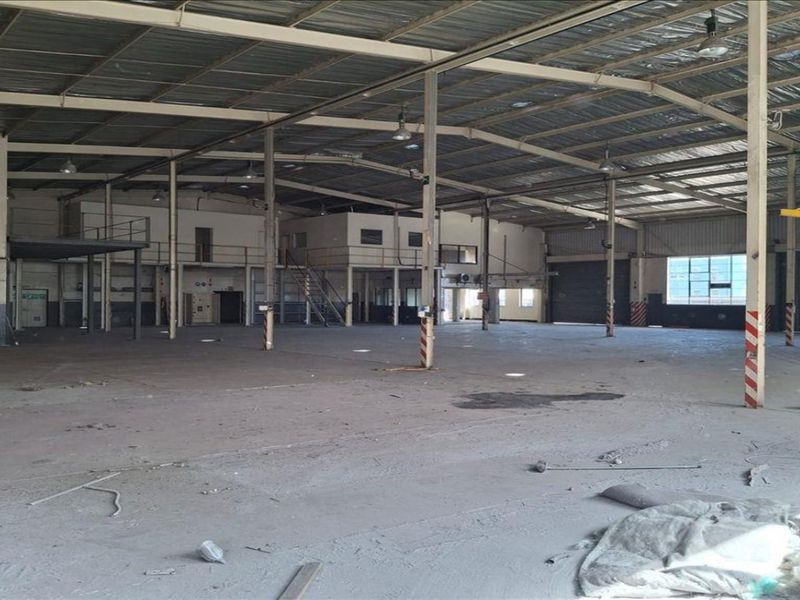 Expansive industrial warehouse space featuring high ceilings, steel portal frame construction, a mezzanine level, and large roller shutter doors for efficient logistics access.
