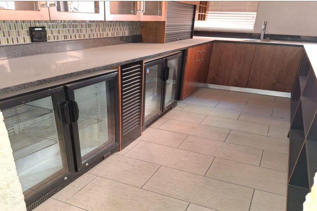 A well-maintained industrial-style kitchen area featuring stone countertops, built-in under-counter glass door refrigeration units, and modern tiled flooring.