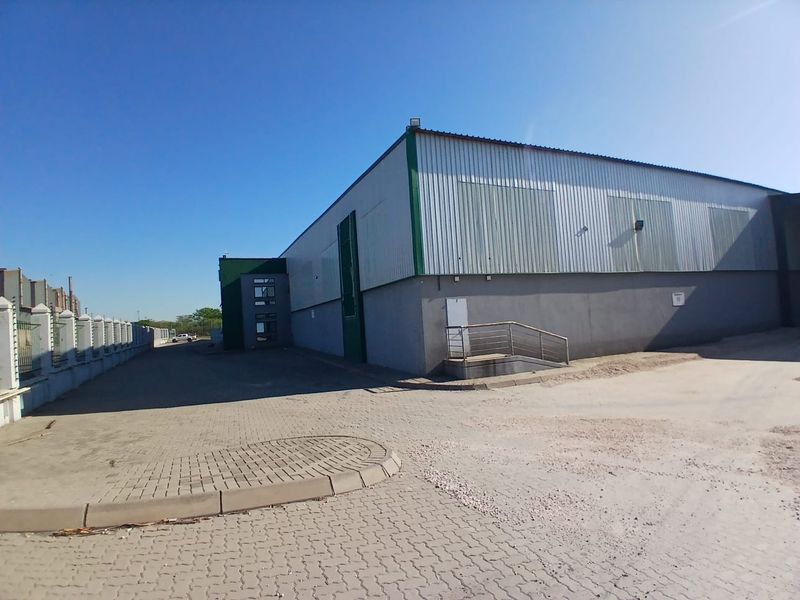Exterior view of an industrial warehouse facility featuring metal cladding, concrete base, and paved access area.