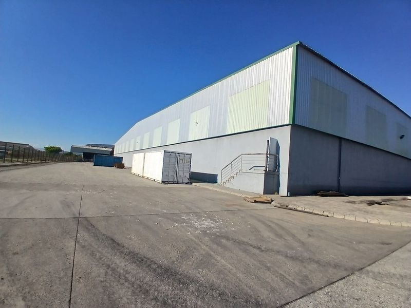 Exterior view of an industrial warehouse facility featuring metal cladding, concrete hardstand area, and external staircase access.