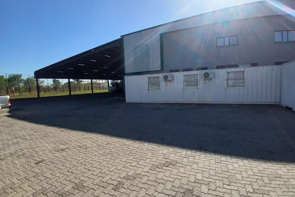 Industrial property featuring a large covered loading or storage area, paved yard space, and modular office units with external air conditioning units.