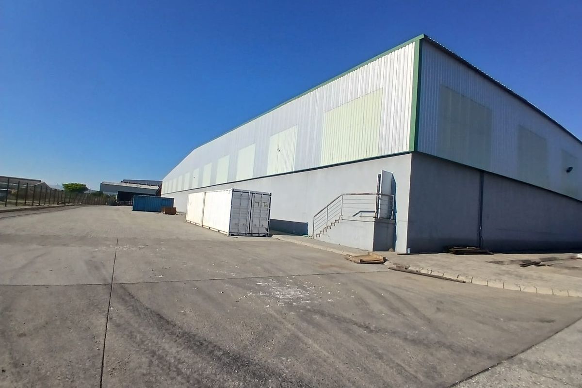 Exterior view of an industrial warehouse facility featuring metal cladding, concrete hardstand area, and external staircase access.