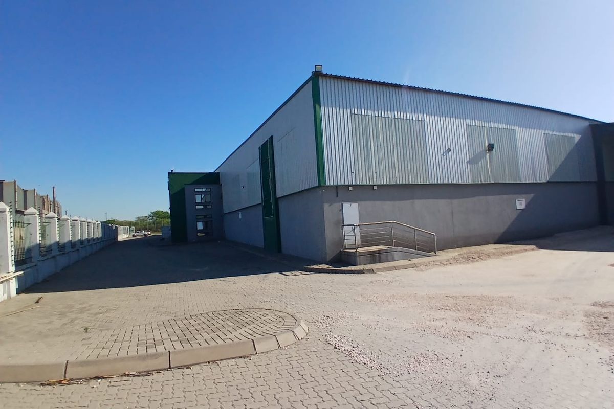 Exterior view of an industrial warehouse facility featuring metal cladding, concrete base, and paved access area.
