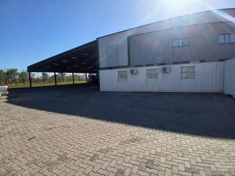 Industrial property featuring a large covered loading or storage area, paved yard space, and modular office units with external air conditioning units.