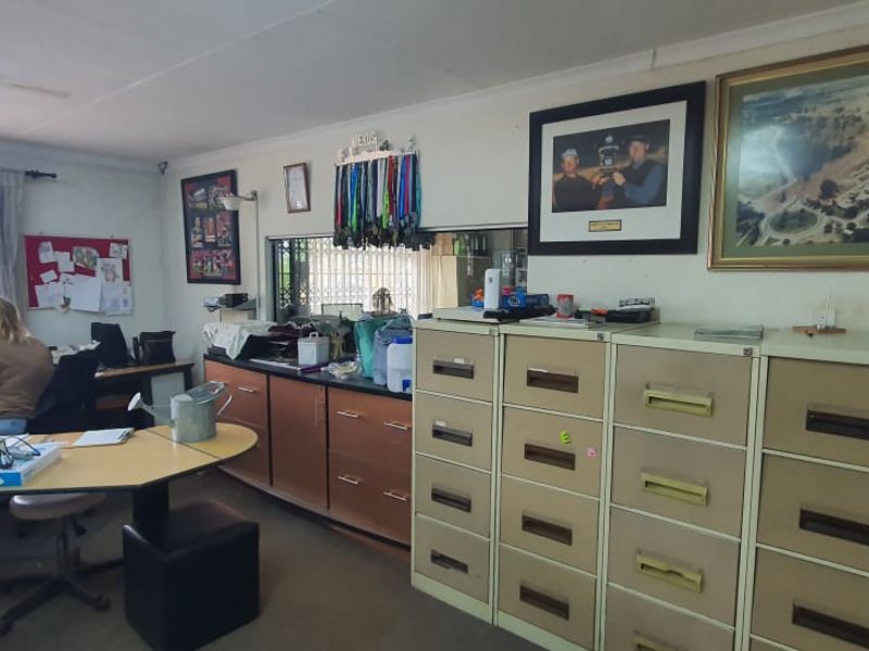 A functional office space featuring built-in cabinetry, metal filing cabinets, and security gates, providing a practical administrative work environment.