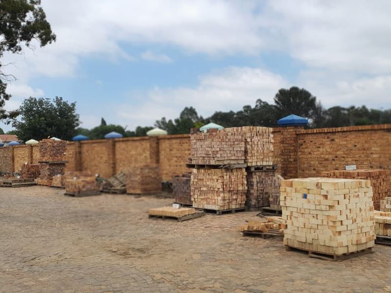 An outdoor storage yard featuring a paved surface and a long perimeter brick boundary wall.
