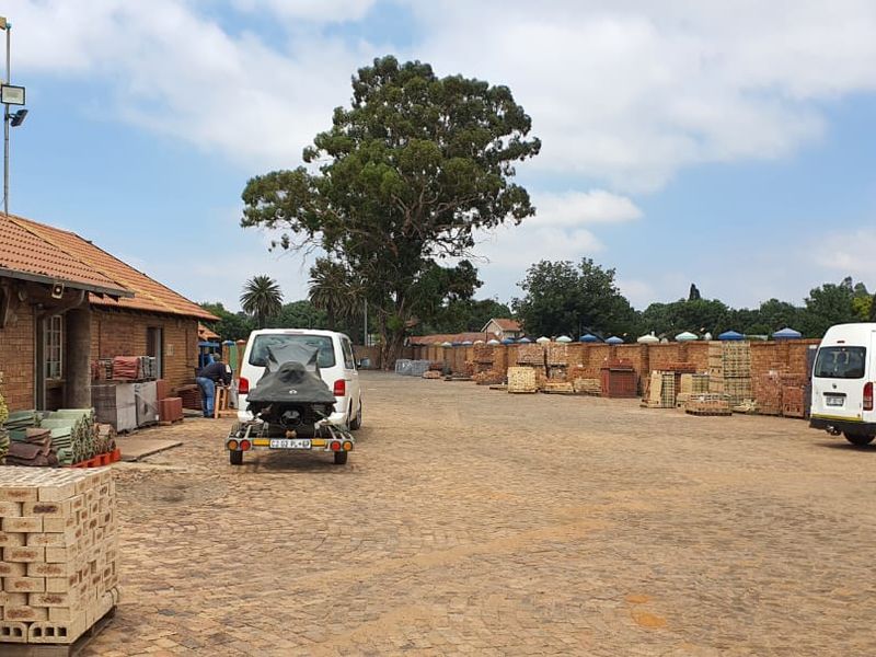 Spacious exterior yard area featuring paved ground, brick building facade, and perimeter brick walling, suitable for commercial storage or operational use.