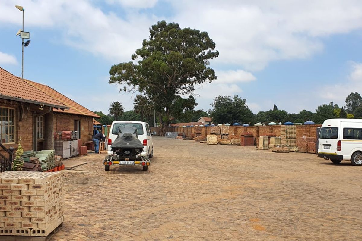 Spacious exterior yard area featuring paved ground, brick building facade, and perimeter brick walling, suitable for commercial storage or operational use.