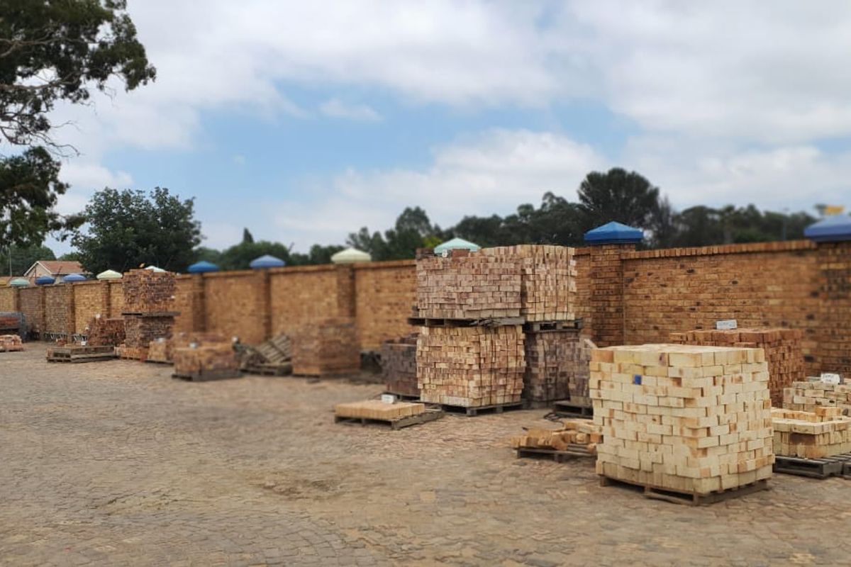 An outdoor storage yard featuring a paved surface and a long perimeter brick boundary wall.