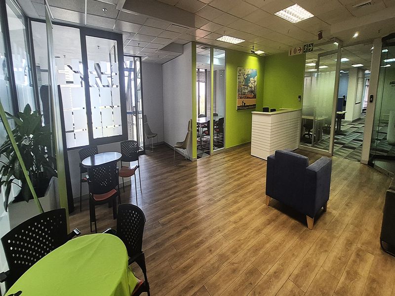 Modern office reception area featuring glass partitions, laminate flooring, recessed lighting, and a built-in reception desk.