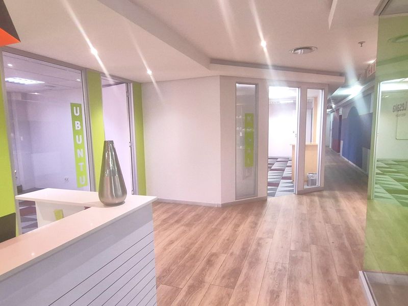 Modern office reception area featuring glass partition walls, laminate flooring, and recessed lighting, creating a bright and professional workspace environment.